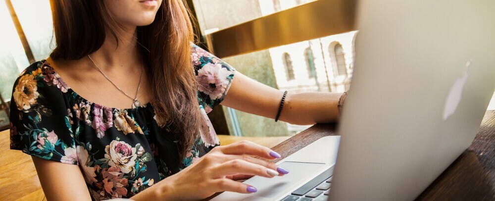 A woman typing on her laptop next to the window