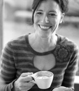 A woman holding her  cup of coffee and smiling